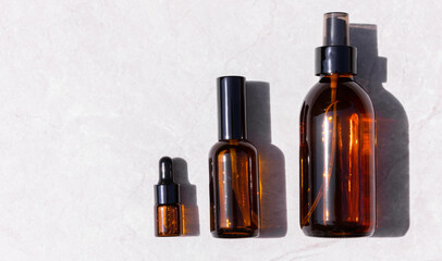 Serum oil essence and face tonic in brown glass bottle on light gray background with shadow. Mockup of cosmetic products for skin care. Top view.Space for copy.