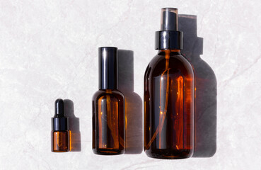 Serum oil essence and face tonic in brown glass bottle on light gray background with shadow. Mockup...