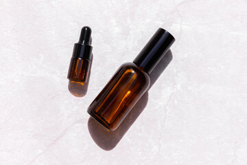 Serum oil essence and face tonic in brown glass bottle on light gray background with shadow. Mockup...