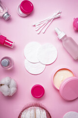 Cotton pads, cotton buds and cosmetic on a pink background, top view, vertically. Spa concept.