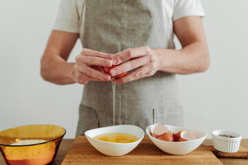 Man in apron cooking, in progress. Eggs, flour, salt on the table, cutting board and knife. Dough Ingredients.