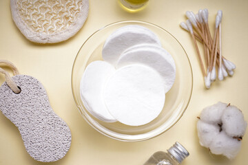 Spa concept. Cotton pads and personal care products on a yellow background, close-up. Top view.