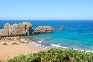 An extensive beach with transparent waters and surrounded by vegetation.