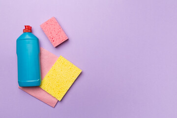 Bottle with dishwashing detergent and sponges on color background, top view