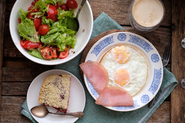 Breakfast. Salad with tomatoes and lettuce, scrambled eggs with bacon and a piece of crumble