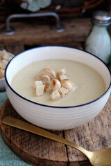 Cream soup with mushrooms and crackers.Wooden background, side view