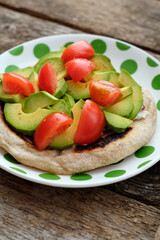 Flatbread with avocado and tomato. Wooden background, side view