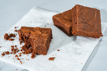 cubes of chocolate brownies on a white plate on a marble table.