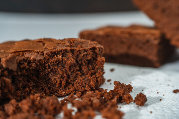 Close up of cubes of chocolate brownies on a white plate on a marble table.