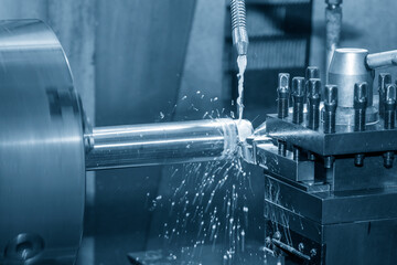 The lathe machine cutting  the metal  shaft parts with water base coolant method.