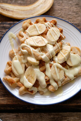 Waffles with banana and white chocolate. Wooden background. Top view. 