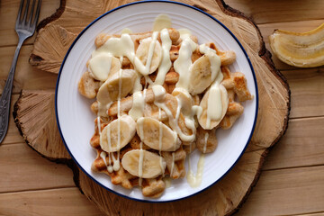 Waffles with banana and white chocolate. Wooden background. Top view. 