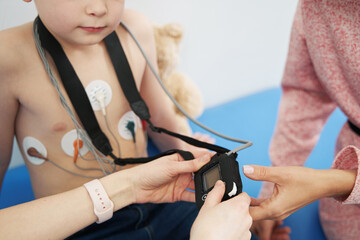 Doctor examining little boy with ECG holter monitor in clinic