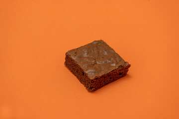 Chocolate brownies on an orange surface.