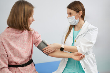 Doctor checking woman blood pressure in clinic