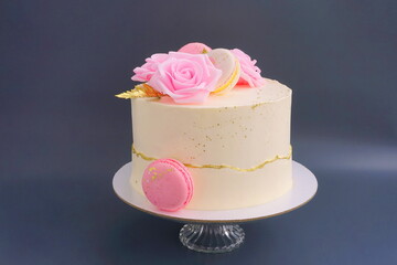 Wedding cake with pink roses. Sweet confection with white cream  and decorated  flowers. Pastry on a light grey background. Dessert for birthday, for Valentine's day, for Mother's day.