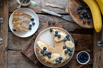 Banana cake with blueberries and white chocolate. Wooden background, top view