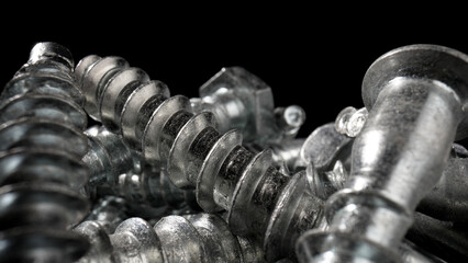 Pile of steel chrome screws. Stainless steel bolts, metal anchor bolts on the table. Metallic helical carving joinery. Macro close up.