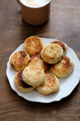 Cottage cheese pancakes with condensed milk. Side view, wooden background. Syrnik