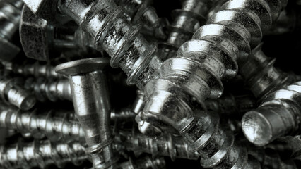 Pile of steel chrome screws. Stainless steel bolts, metal anchor bolts on the table. Metallic...