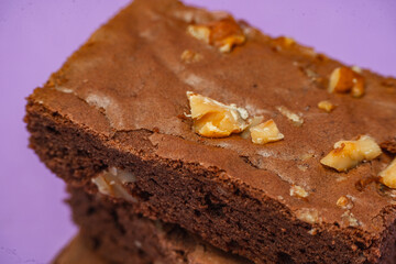 Homemade chocolate brownie squares with pecan pieces. Orange Background. Natural, healthy food concept.