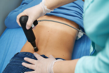 Female patient receiving extracorporeal shockwave therapy in clinic