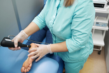 Doctor performing shockwave therapy procedure in clinic