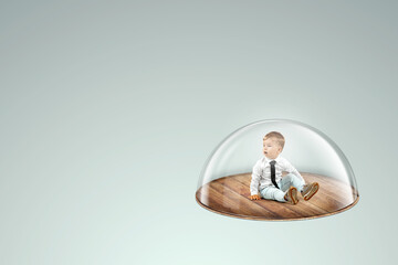 Child safety, overprotection, a little boy sits under a glass dome, cap. Vaccinations, protection...