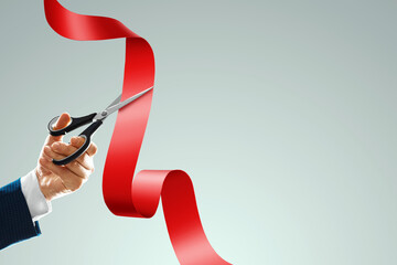 Grand opening with red ribbon and scissors. A businessman's hand holds scissors cuts a red ribbon on a light background. Close-up, copy space. - obrazy, fototapety, plakaty