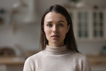 Positive serious millennial model girl home female head shot portrait. Beautiful young adult Caucasian woman looking at camera, posing in apartment. Front profile picture - Powered by Adobe