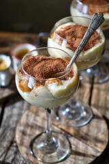 Portioned tiramisu in a glass. Wooden background, side view