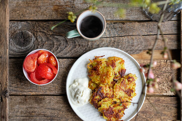 Draniki and cucumbers on a blue plate. Top view, wooden background