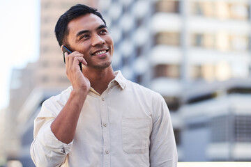 An Asian businessman stands in the city taking a call on his cellphone