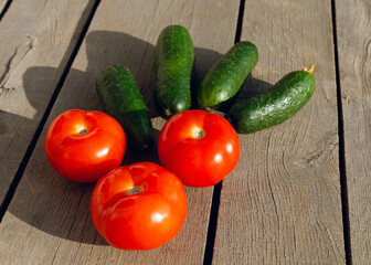 tomatoes with cucumbers lie on a wooden table