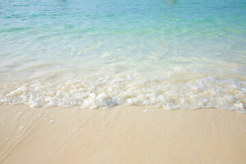 Fototapeta na wymiar Soft ocean waves on the sandy beach, blue water.