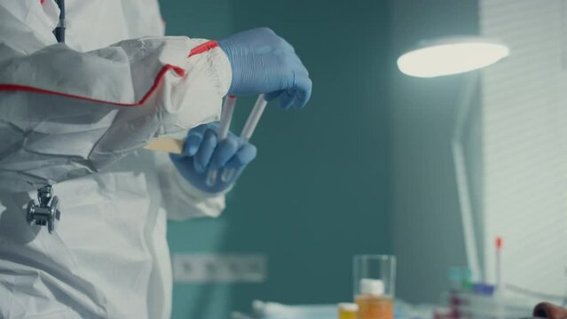 Nurse taking mouth swab in protective suit gloves infectious department closeup.