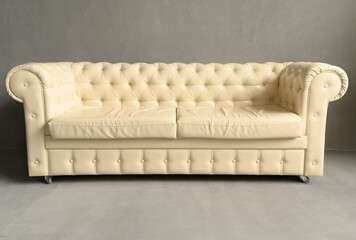White leather sofa in a dark studio. Modern comfortable cozy.