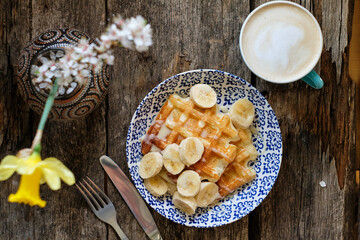 Obraz na płótnie Canvas Waffles with banana and white chocolate. Wooden background. Top view.