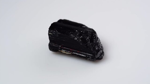 black tourmaline scherl rough specimen on the white background turning table