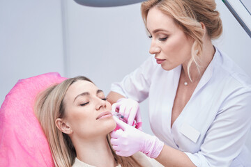 Experienced aesthetic clinic doctor giving beauty injection to patient