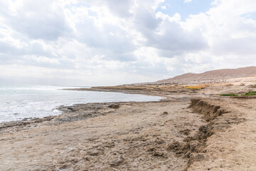 Exotic view of the sinkhole area of the Dead Sea on a stormy winter day. PhotoStorm and rain at the Dead Sea coastline. Salt crystals at sunset. The texture of the Dead sea. Salty seashore. High