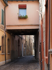 Fototapeta na wymiar Ferrara, Italy. Downtown, medieval cobbled street with archway.