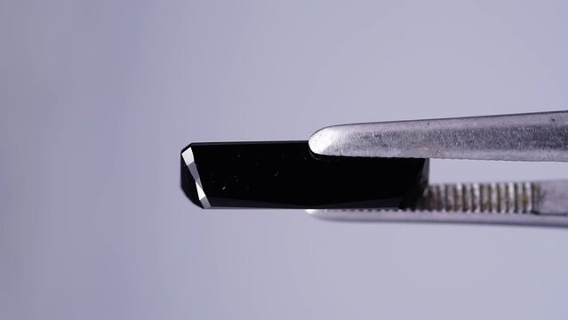 black tourmaline scherl rough specimen in the tweezers