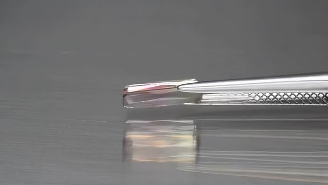 natural bi-color polychromatic tourmaline baguette cut in the tweezers