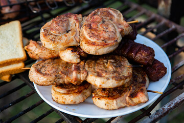 A large variety of grilled meat on the fire outside. Picnic with meat: sausages, pork steak, chicken breast with vegetables. 