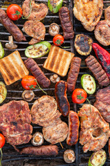 A large variety of grilled meat on the fire outside. Picnic with meat: sausages, pork steak, chicken breast with vegetables. 