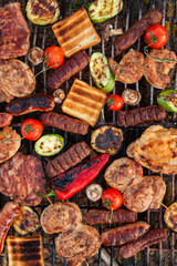 A large variety of grilled meat on the fire outside. Picnic with meat: sausages, pork steak, chicken breast with vegetables. 