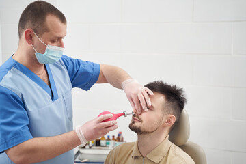 Fototapeta premium Doctor treating patient runny nose in clinic