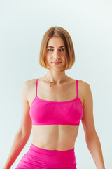 Fototapeta na wymiar Photo of athletic beautiful lady in pink sportswear on a white background posing for the camera. Vertical