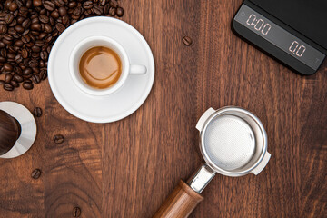 Cup of espresso on walnut table with espresso making equipment all around 
